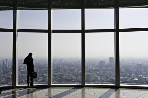 Man in front of tall windows looking over a city scape