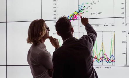 Two people looking at a scatter graph on screen