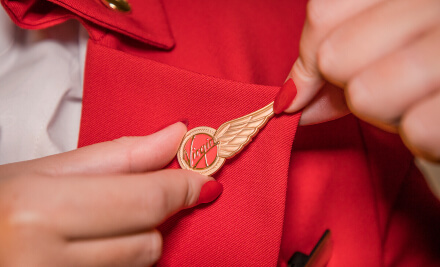 Female Virgin Atlantic employee attaching Virgin Atlantic pin to lapel