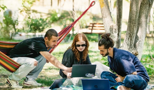 Three friends out in the nature engaged on a laptop