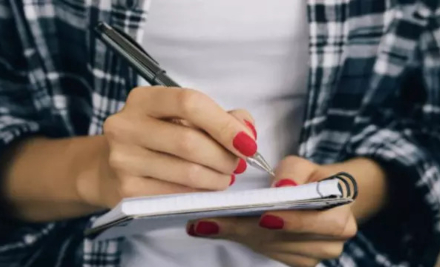 Person writing on pad with ballpoint pen