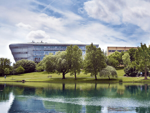 University of Surrey's picturesque lake with trees and buildings in the backdrop