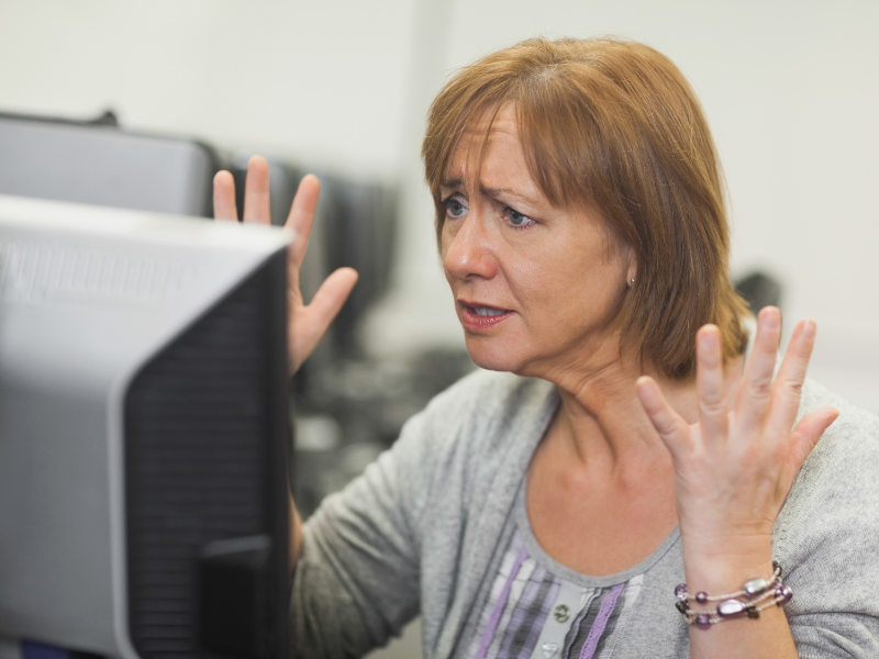 Woman at computer throwing hands in frustration